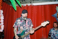 a man playing a bass in front of a red curtain